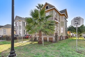 A residential area with a house featuring a balcony, a palm tree, and a 'ONE WAY' street sign. - 1 Mi to Beach! Coastal Couples Escape in Galveston (Galveston)