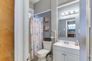 A bathroom with a shower curtain, toilet, sink, and mirror. - 1 Mi to Beach! Coastal Couples Escape in Galveston (Galveston)