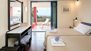 Ein Hotelzimmer mit Bett, einer Bank, einem Schreibtisch, einem Stuhl und einem Balkon mit Meerblick.