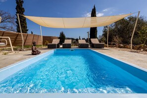 A swimming pool with lounge chairs and a canopy.
