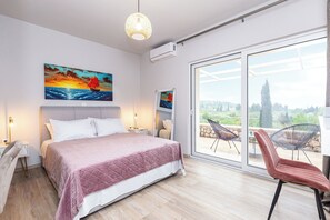 Un dormitorio con cama, un ventanal grande y un balcón con sillas.