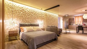 Une chambre moderne avec un grand lit, des tables de chevet, un bureau et un coin cuisine.
