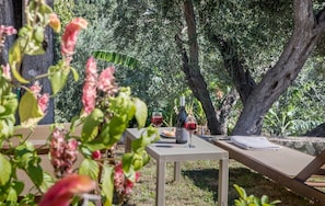 An outdoor dining area with a table, chairs, and a bottle of wine.