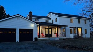 A two-story house with a covered front porch, a garage, and a small detached shed.