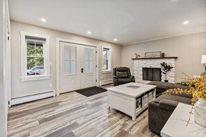 A living room with a fireplace, a coffee table, and a leather chair. - Spacious Colonial | Large Groups | Fire Pit (Brewer)