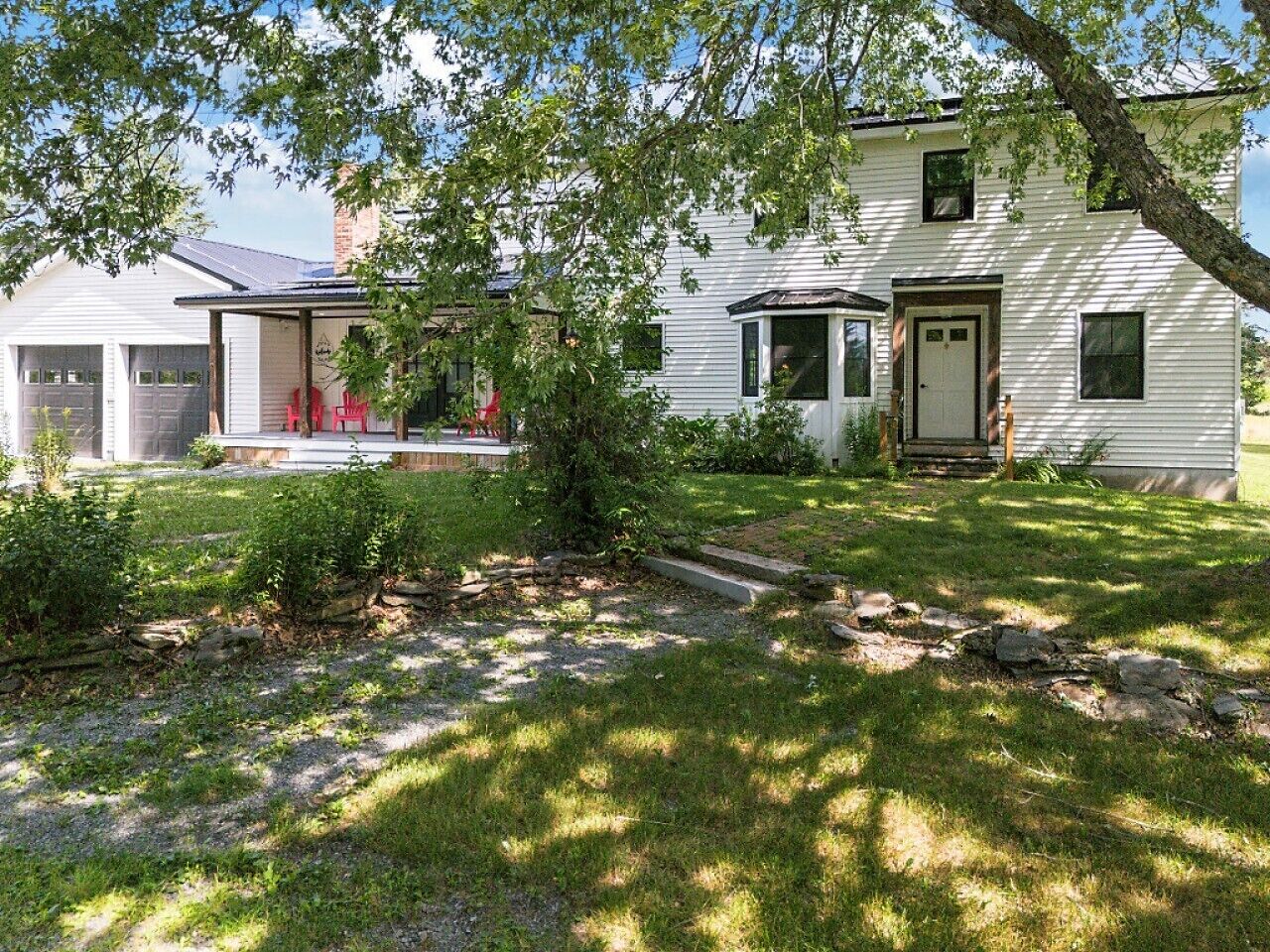 A two-story house with a front porch, a stone pathway, and a well-maintained lawn.