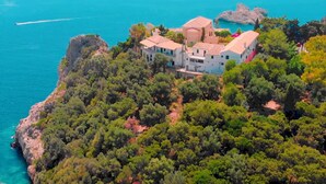Um imóvel costeiro com vários edifícios rodeados por vegetação densa e vista para o mar.