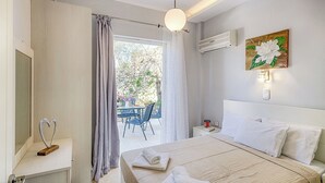 Quarto com cama, mesa de cabeceira, cortinas na janela, ar condicionado e um quadro na parede.