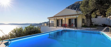 Uma área de piscina com vista ampla para o mar e montanhas ao fundo.