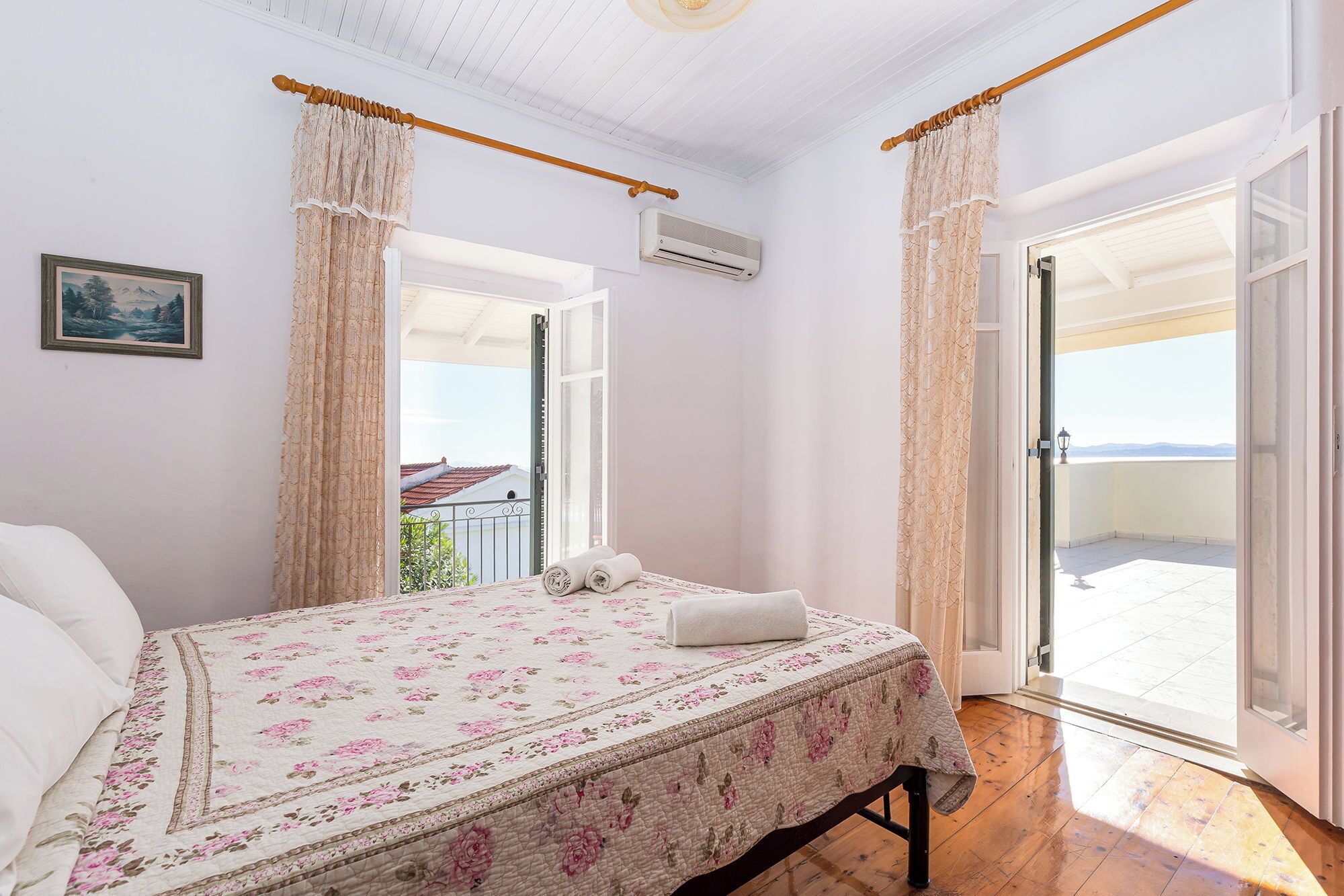 Ein Schlafzimmer mit einem Bett, einem Fenster und einer Tür, die auf einen Balkon führt.
