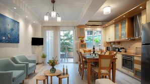 Un salon moderne comprenant un coin repas, une cuisine et une grande fenêtre donnant sur un paysage verdoyant.