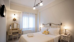 Une chambre à coucher comprenant un lit, des tables de chevet, une commode, un miroir, une fenêtre avec des rideaux et un lustre.
