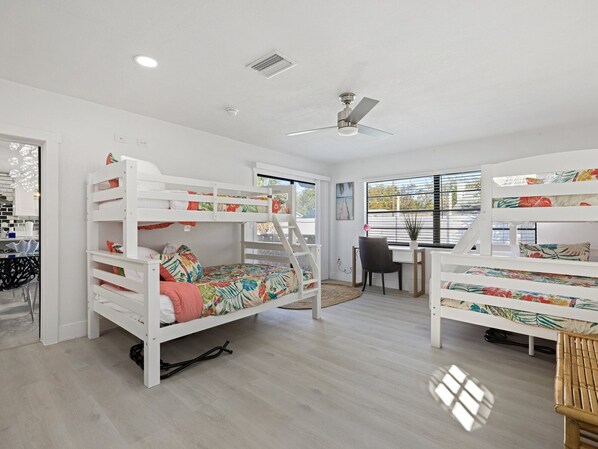 A room with bunk beds, a desk, and a chair.