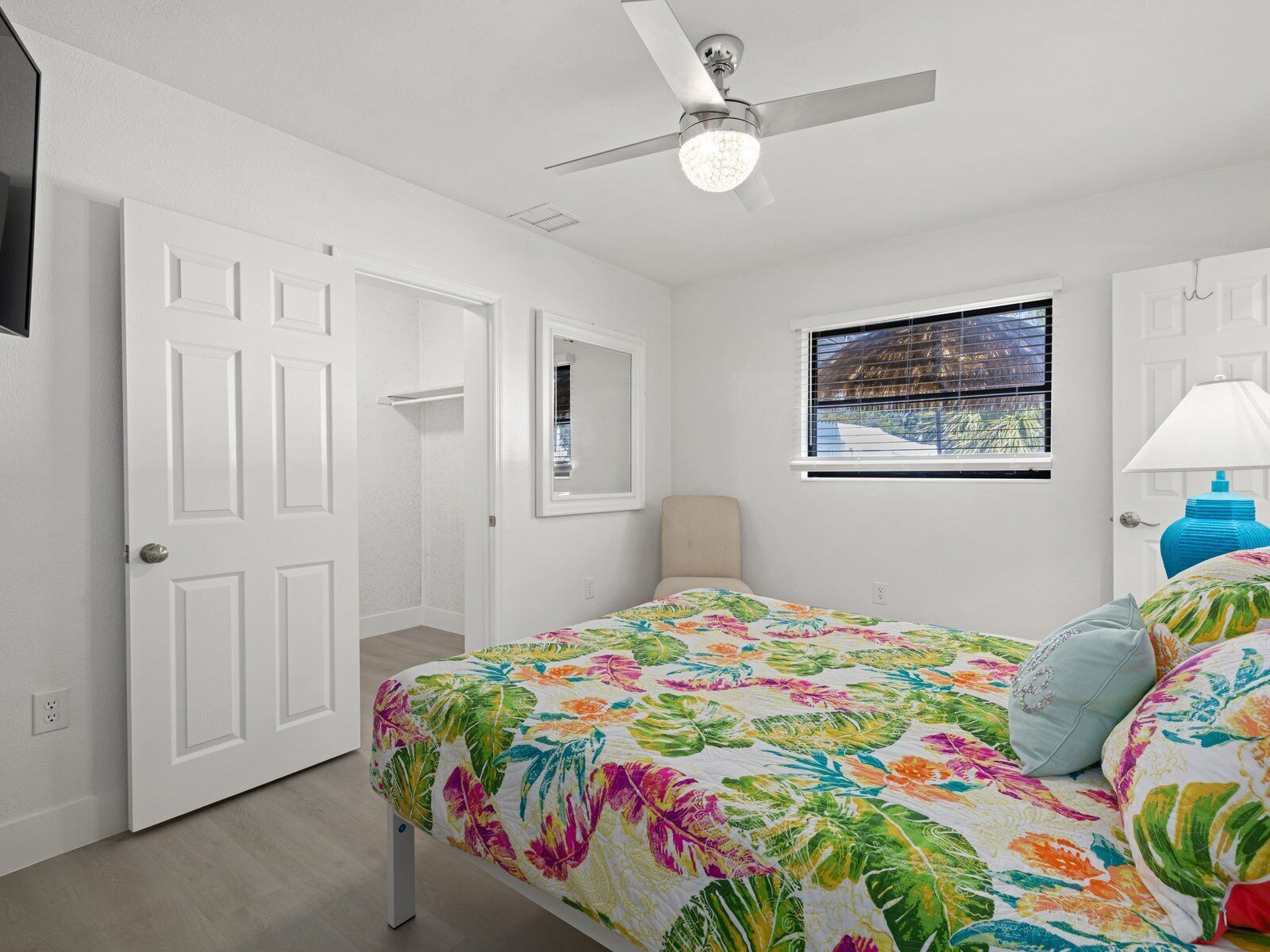 Un dormitorio con cama, ventilador de techo, ventana y puerta.