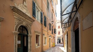 A narrow cobblestone street with historic buildings, a covered passageway, and a signboard. - Studio No2, CasaNova, Corfu old town center (Corfu)