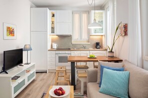 A modern kitchen with white cabinets, a wooden dining table, and a sofa with blue cushions.