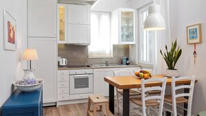 A modern kitchen with white cabinetry, a wooden dining table, and a small stool. - Studio No4, CasaNova, Corfu old town center (Corfu)