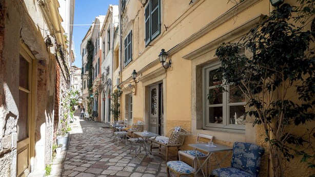 A narrow cobblestone street with outdoor seating, potted plants, and traditional architecture. - Studio No4, CasaNova, Corfu old town center (Corfu)