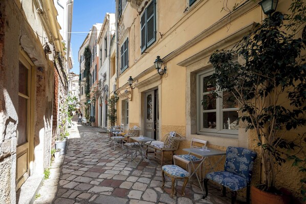 A narrow cobblestone street with outdoor seating, potted plants, and traditional architecture.