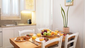 A breakfast table with croissants, fruit, and juice, a potted plant, and a framed picture on the wall. - Studio No4, CasaNova, Corfu old town center (Corfu)