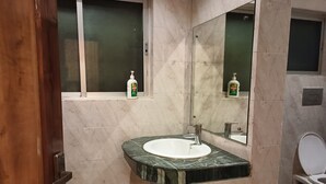 A bathroom with a marble sink, a mirror, and a toilet. - Lilawati's Blue Fox (Sonapur)