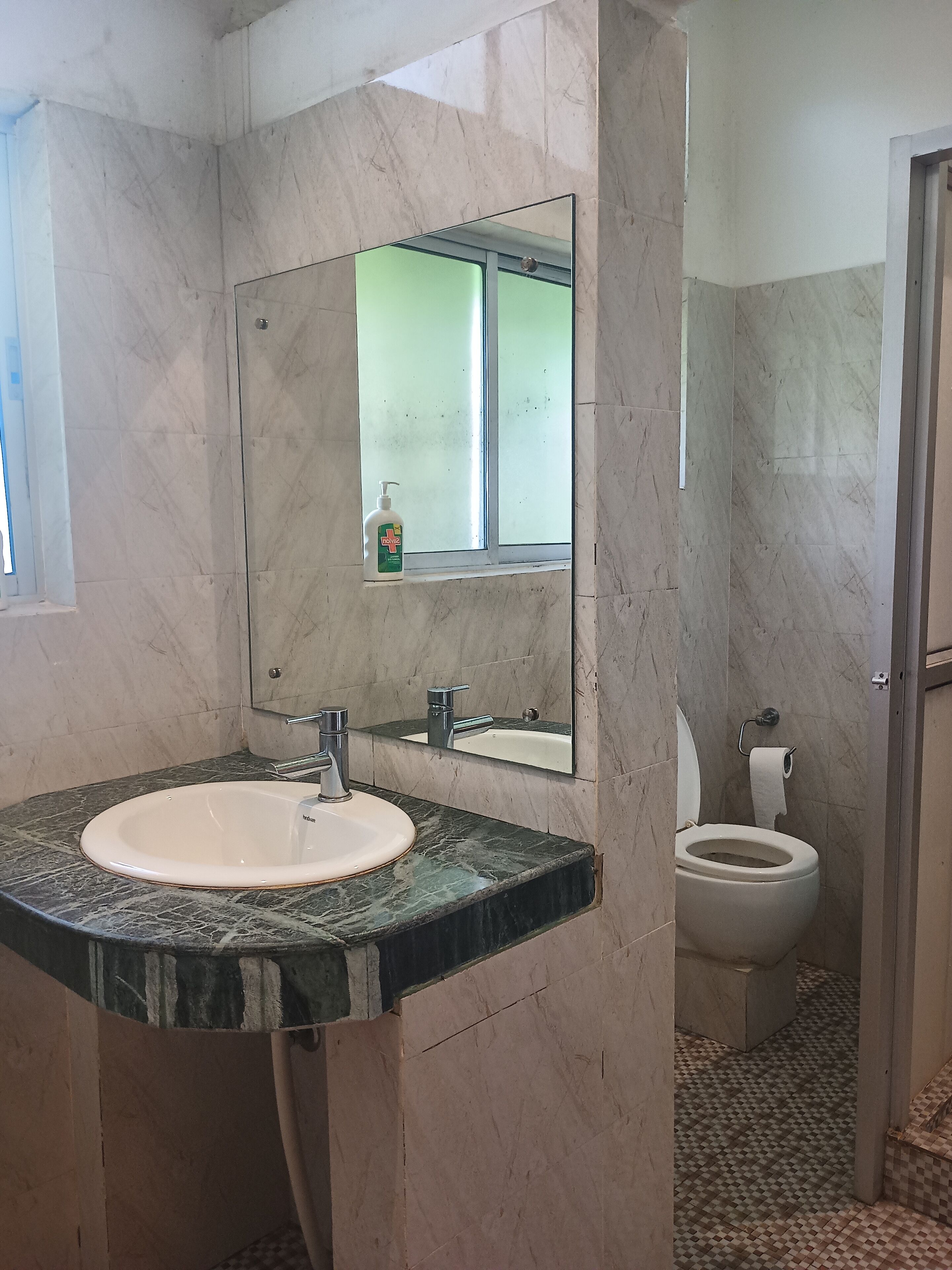 A bathroom with a marble sink, a mirror, and a toilet.