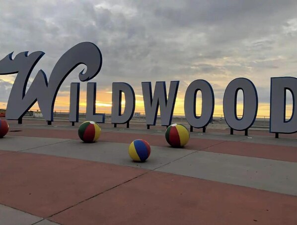 A beach sign with the word "WILDWOOD" and several beach balls in the foreground.