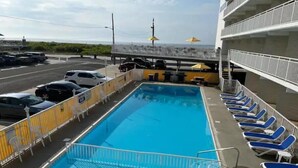 Ein Pool mit blauem Wasser, umgeben von Liegestühlen und einem Zaun.