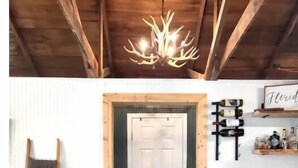 Un interior de madera con una lámpara de araña, una puerta, un estante con botellas y una escalera.