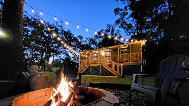 Un patio trasero con un brasero, luces colgantes y una terraza de madera.