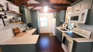 Una cocina con techo de madera, microondas, estufa y ventana.