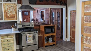 Een keuken met een fornuis, oven, magnetron en houten kastjes. Er is een sterren decoratie aan de muur en een deur met sterspatroon.