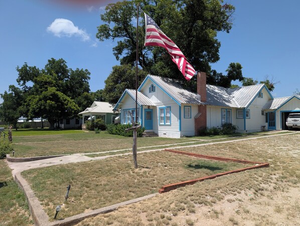A historic building with a flagpole, a flag, and a garage. - Charming, unique 3-bedroom house in Junction with AC, WiFi, Pet Friendly (Junction)