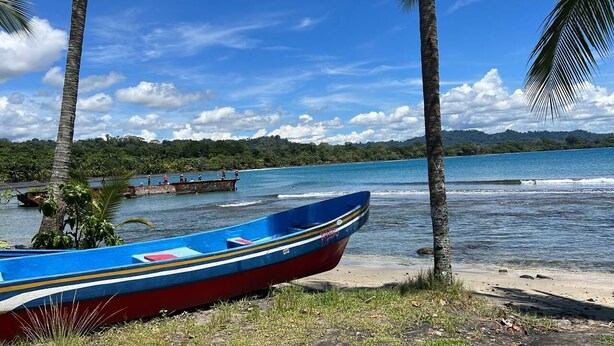 Un bateau sur une plage, avec une vue dégagée sur l’eau et une côte lointaine.