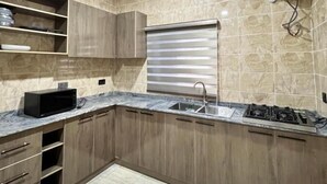 Eine moderne Küche mit Holzausstattung, einer eingebauten Mikrowelle, einem Gasherd und einer Edelstahlspüle.