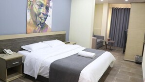 Ein Hotelzimmer mit Bett, Nachttisch und einem Gemälde an der Wand.