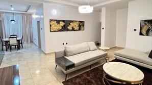 Ein modernes Wohnzimmer mit einer Couch, einem runden Couchtisch und Kunstwerken an den Wänden.