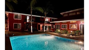A swimming pool with a red building in the background. - Las Palmas Condo: Pool & Beach (Coco)