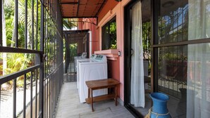 A balcony with a washing machine, a small wooden table, and a blue vase. - Las Palmas Condo: Pool & Beach (Coco)