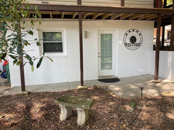 Un edificio blanco con un cartel que dice 'WELCOME', una puerta y un banco al frente.