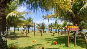 Un parco con giochi per bambini, palme e un cartello con la scritta 'PARQUE INFANT'.