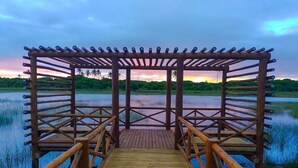 Un pontile di legno conduce a un gazebo con vista su un lago e sulla vegetazione circostante.