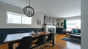 Una cocina moderna con una mesa de comedor de madera, sillas negras y una lámpara de araña.