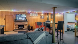 Una sala de estar acogedora con mesa de fútbol, chimenea, televisor y un espacio de descanso cómodo.
