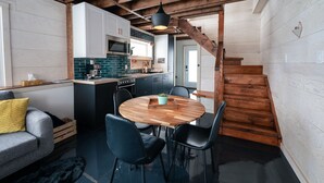 A modern kitchen with white cabinets, a stainless steel refrigerator, and a black hanging light fixture.