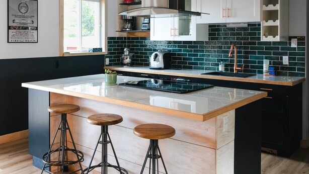 Une cuisine moderne avec un îlot central, des tabourets de bar et une fenêtre.