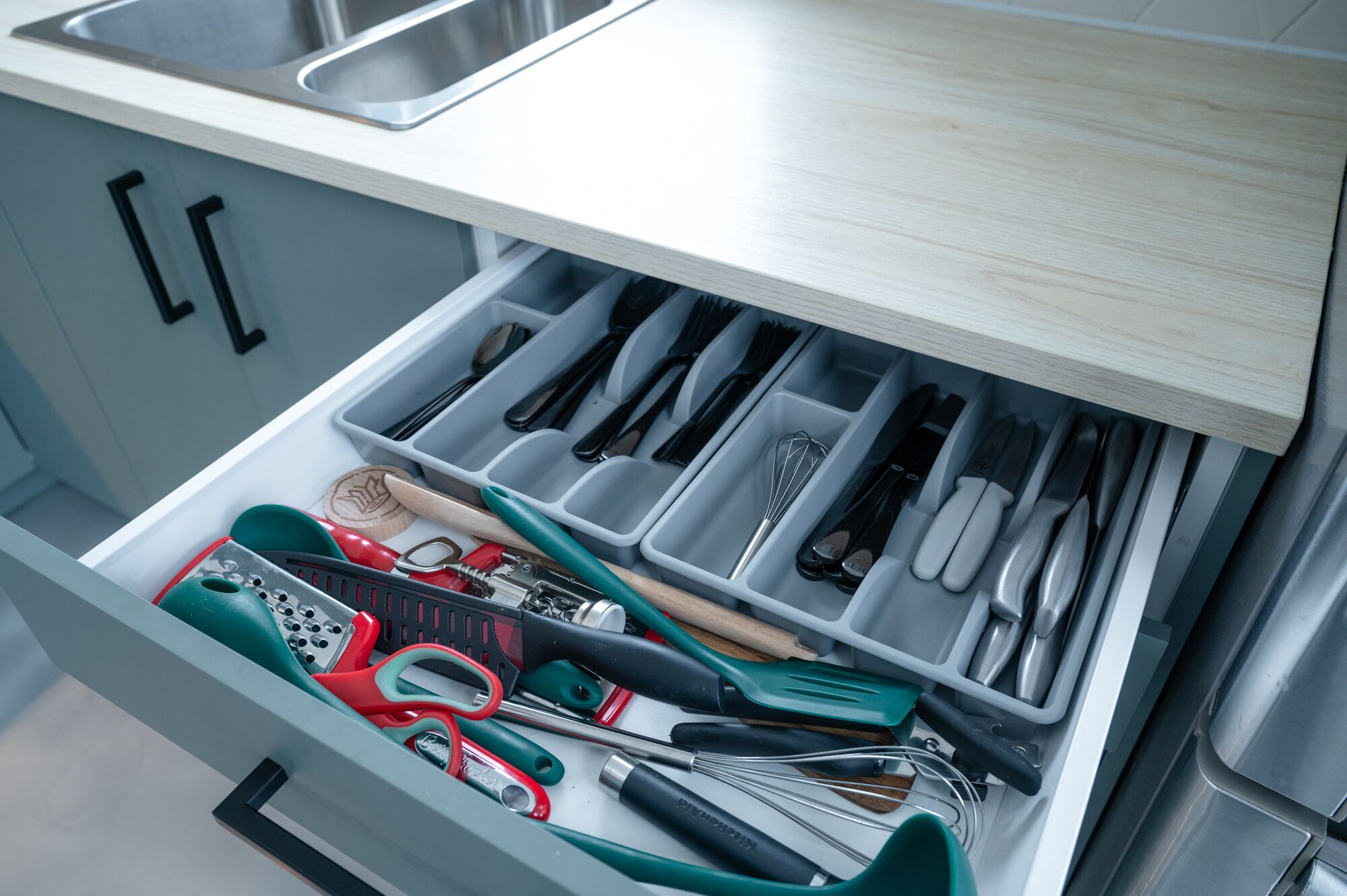 A kitchen drawer with utensils and tools.