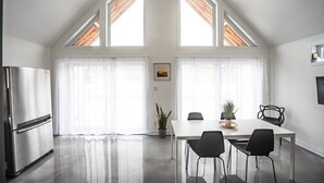Una cocina moderna con zona de comedor, ventanas amplias y un techo con tragaluces.