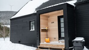 Una cabaña moderna con interior de madera, el número 644 en la pared y un techo cubierto de nieve.