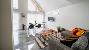 Una sala de estar moderna con comedor, ventanas grandes y un televisor de pantalla plana.